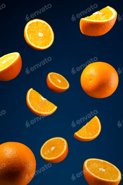 Preview: Vertical shot of some orange slices in the levitation on a dark blue background.