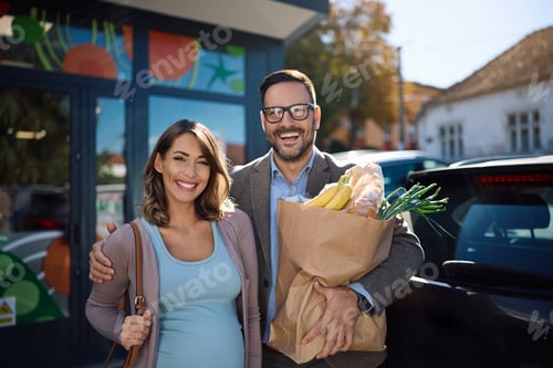 Preview: Happy pregnant couple feeling satisfied after buying in supermarket and looking at camera.