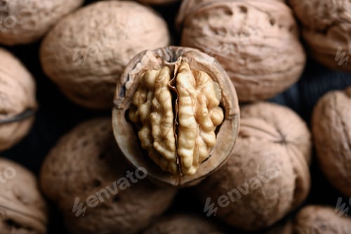 Preview: Cracked walnut with kernels on heap of whole walnuts