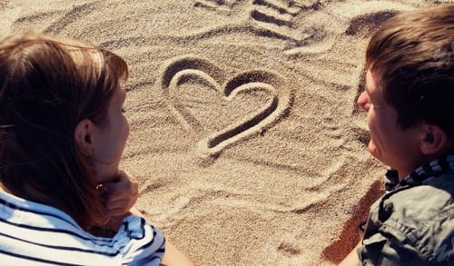 Preview: People drawing heart at sand.