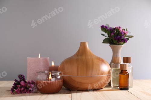 Preview: Spa composition with flowers and burning candles on wooden table against grey background, closeup