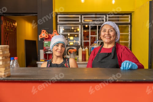 Preview: Two smiling cooks posing in their fast food restaurant kitchen