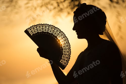 Preview: Woman with vintage fan at sunset