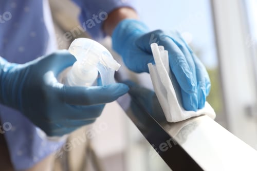 Preview: Woman in latex gloves cleaning railing with wet wipe and detergent indoors, closeup