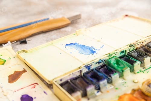 Preview: Drawing accessories set: brushes, pencils, watercolor on brown concrete. Side view, selective focus