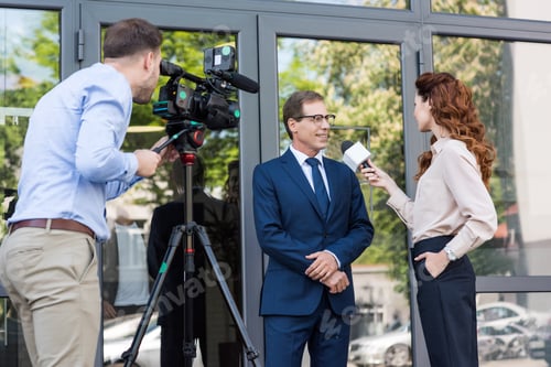 Preview: cameraman and news anchor interviewing businessman near office building
