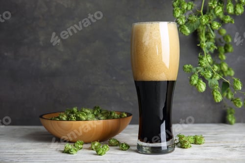 Preview: Composition with tasty beer and fresh green hops on wooden table. Space for text