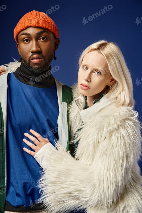 Preview: blonde woman embracing african american man in winter attire of blue backdrop, multiethnic couple