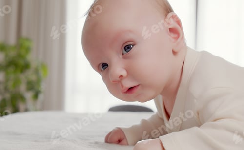 Preview: Portrait of a newborn baby looking at the camera. One-month-old baby is lying on his tummy.