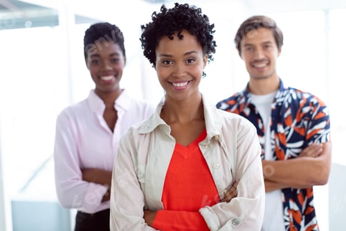 Preview: Front view of young diverse business people with arms crossed looking at camera in a modern office