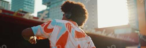 Preview: man wearing shirt listening to music in headphones and dancing on urban city background
