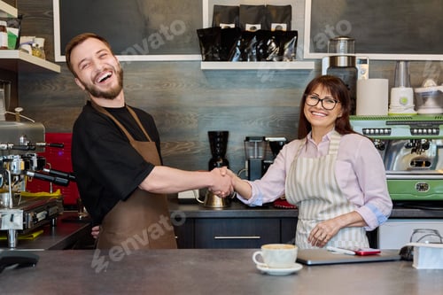 Preview: Colleagues, partners, man and woman shake hands, in coffee shop