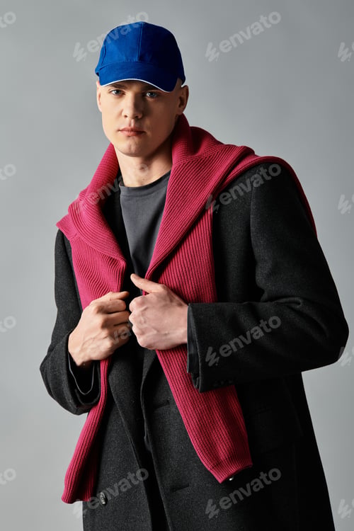 Preview: A young man stands confidently, wearing a cozy sweater over a sleek coat, expressing modern fashion.