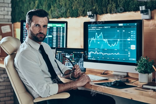 Preview: Handsome young modern man in formalwear looking at camera while sitting in the office