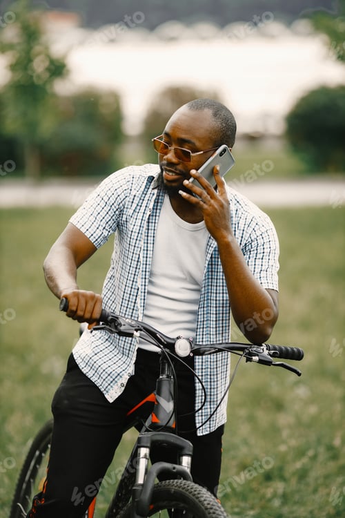 Preview: Black american man in a sunglasses near his bicycle using his phone