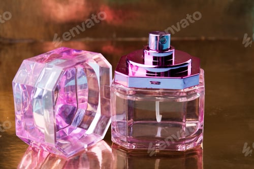 Preview: Pink glass perfume bottle on a reflecting surface.