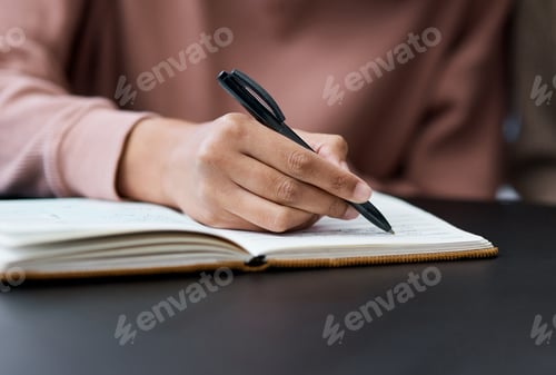 Preview: Shot of an unrecognisable woman writing in a notebook while working from home