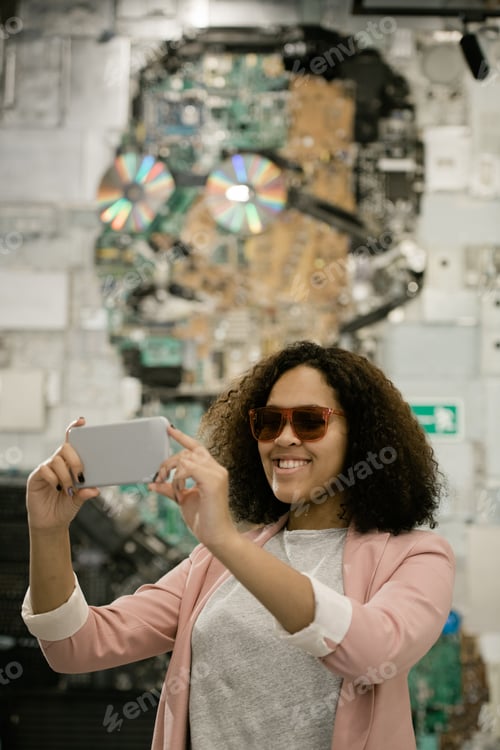 Vista previa: Feliz joven turista intercultural con smartphone haciendo selfies