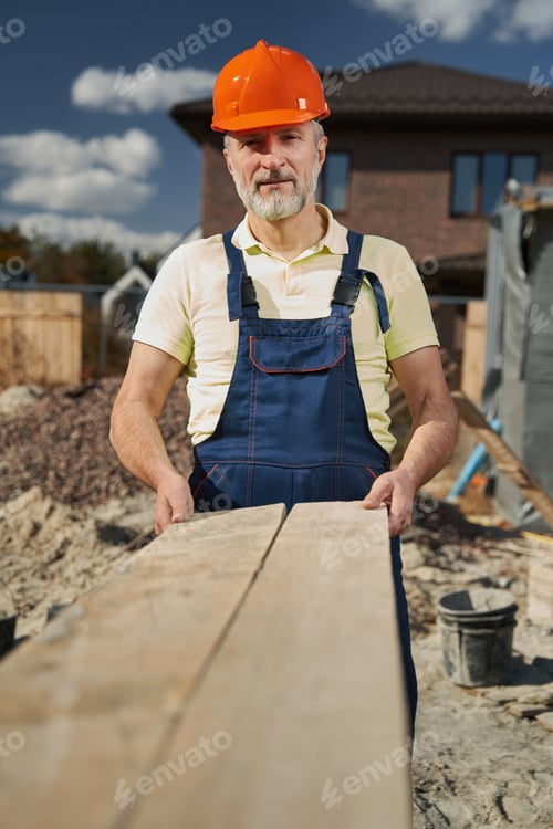 Preview: Senior builder stretching out board to camera