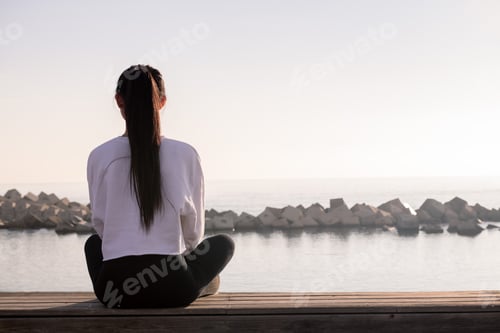 Preview: rear view of a young woman sitting meditating