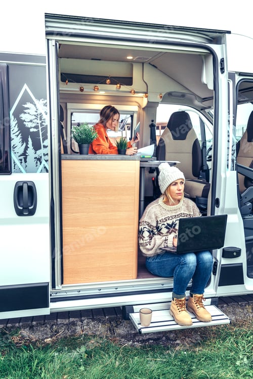 Preview: Woman teleworking sitting in the door of a camper van