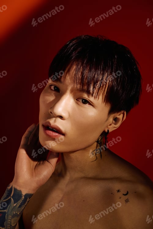 Preview: Stylish young asian man poses confidently against a vibrant red backdrop in an artistic portrait