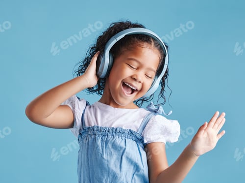 Preview: Adorable little hispanic girl standing with her eyes closed and looking happy while wearing headpho