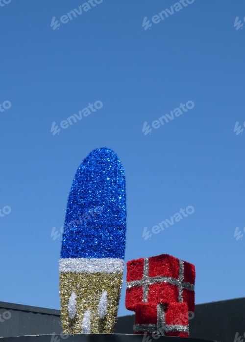Preview: Christmas decorations,surfboard covered in tinsel against clear blue sky with space for text