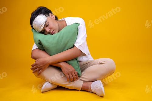 Preview: Full Body of Teenage Boy Sleeping While Putting Head on Pillow and Sitting on Yellow Background
