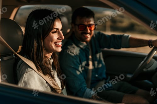 Preview: Happy couple driving car on road trip during sunset