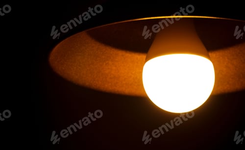 Preview: Closeup of a vintage light bulb illuminating a dark room