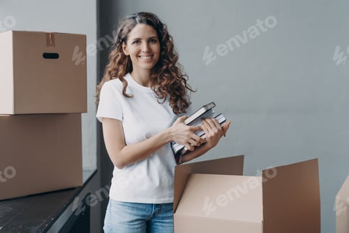 Preview: Happy european woman unpacking boxes and taking off books and notes. Young student in campus room.