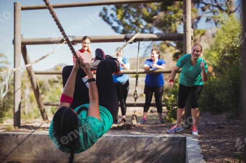 Preview: Fit woman climbing a rope during obstacle course training