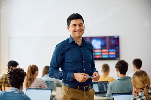 Preview: Happy teacher during computer class at high school looking at camera.