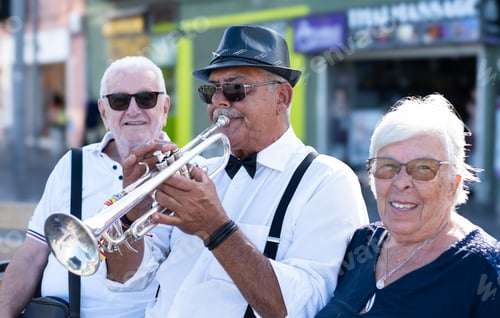 Preview: Portrait of jazz artist in black hat and sunglasses playing trumpet in street.