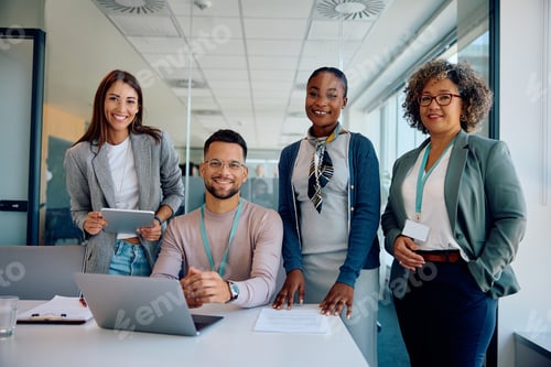 Preview: Happy multiracial business team working in the office and looking at camera.