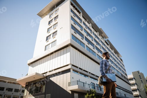 Preview: Man holding laptop while standing by building in city