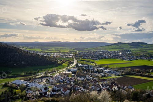 Preview: A town with roads, fields, pastures against the backdrop of silhouettes of hills and a cloudy sky