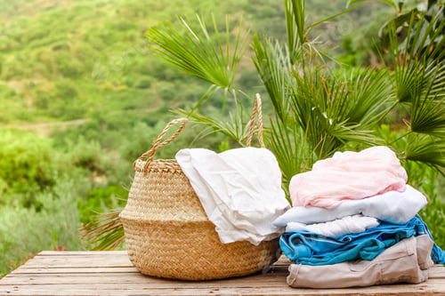 Preview: Basket with clean and dry laundry on wooden table on nature background in sunny day