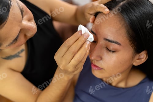 Preview: Makeup artist applying cosmetic product on young woman