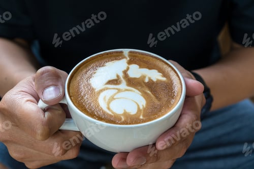 Preview: Closeup man hand holding the cup of coffee with latte art, art and drink concept