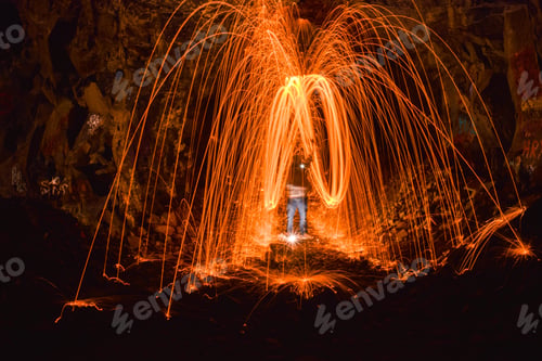 Preview: Long exposure shot of a person rotating a burning steel wool in a cave