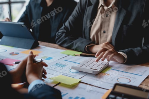 Preview: Business people in a meeting and using a calculator to calculate, plan, analyze, create graphs and c