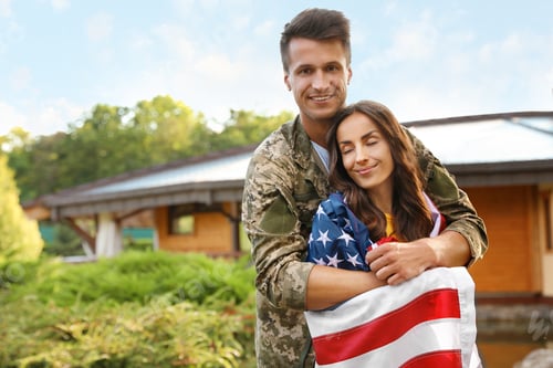 Vista previa: Man in military uniform with American flag and his wife outdoors