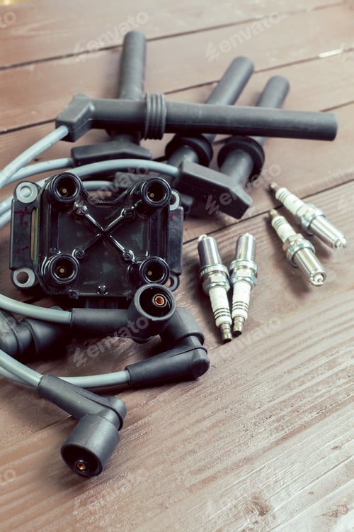 Ignition coil and spark plugs on wooden background
