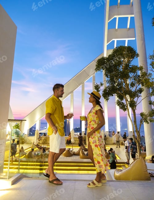 Preview: couple men and women having dinner during sunset at a rooftop restaurant looking out over the city