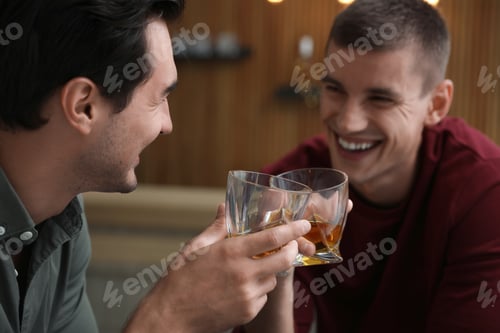 Preview: Young men drinking whiskey together in bar