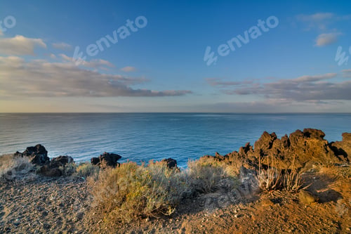 Preview: High angle shot of a seashore in canary islands in spain with a cloudy blue sky in the background