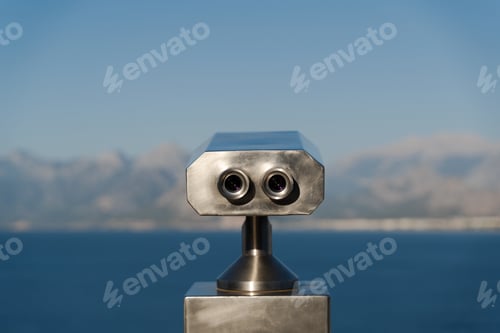Preview: coin operated binoculars in front of mountains and sea