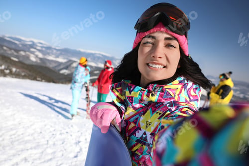 Preview: Young woman with snowboard taking selfie at ski resort. Winter vacation